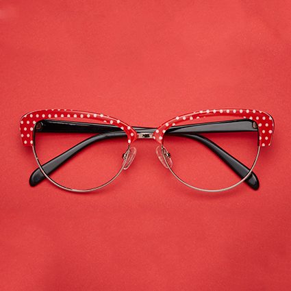Red-rimmed eyeglasses with white polka dots on the upper frame.