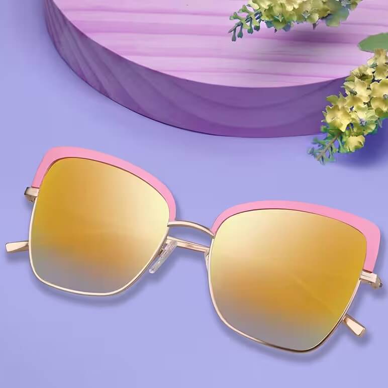 Gold-rimmed sunglasses with pink accents and yellow mirrored lenses on a purple surface.