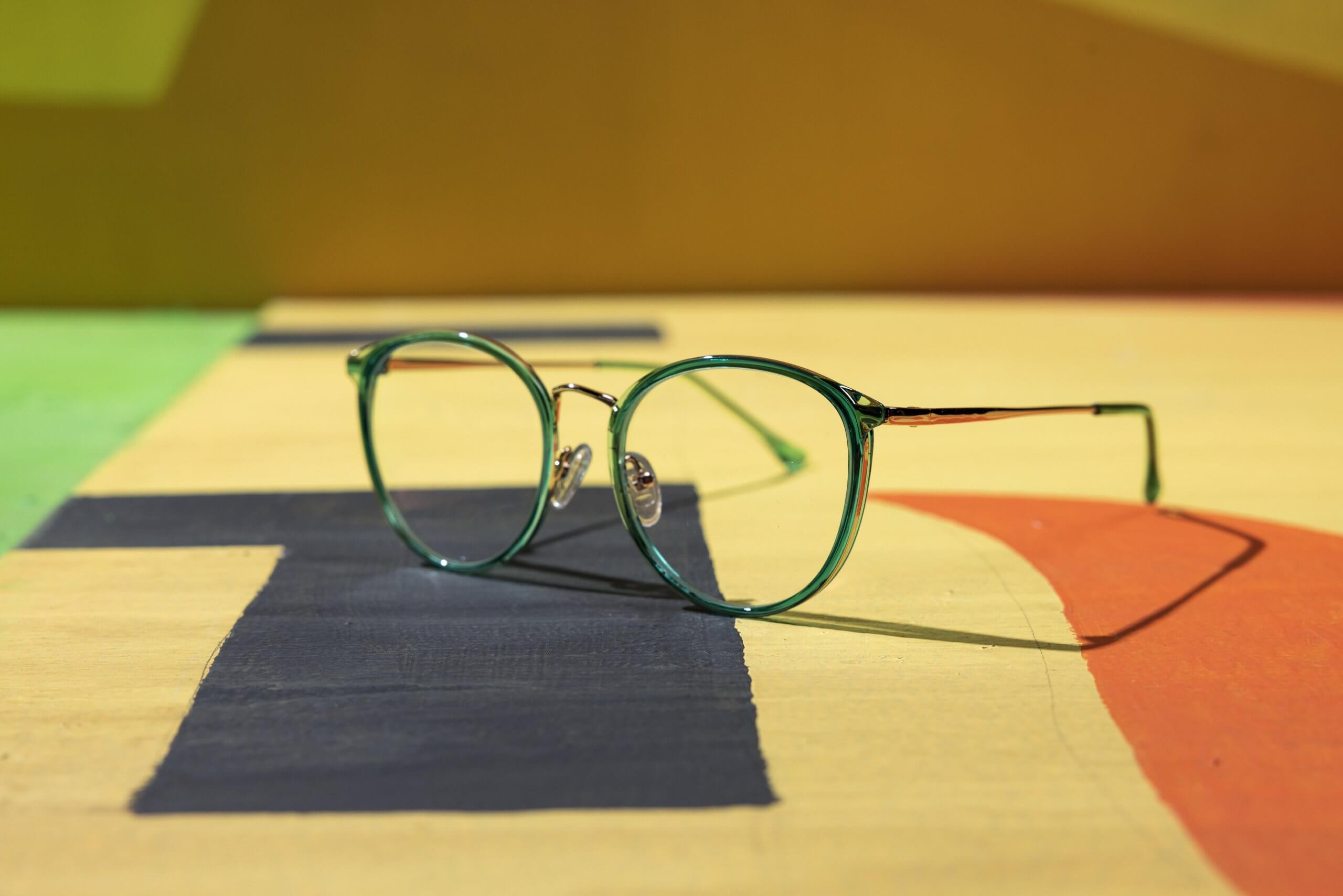 Green-rimmed eyeglasses with clear lenses and nose pads.